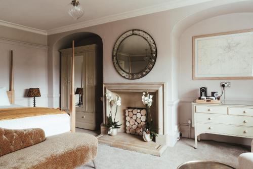 a bedroom with a bed and a mirror and a fireplace at The Falcon Inn in Painswick