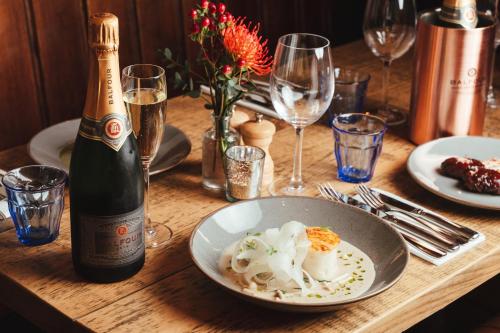 a table with a bowl of pasta and a bottle of wine at The Falcon Inn in Painswick
