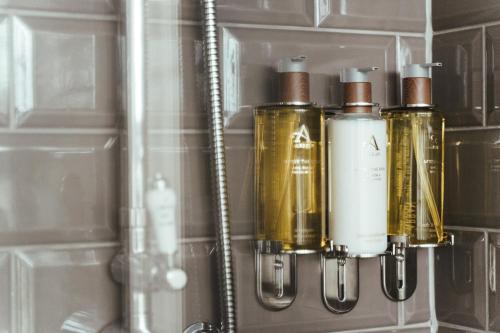 a shelf with four bottles on it in a bathroom at The Falcon Inn in Painswick