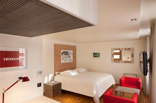 a bedroom with a bed and two red chairs at Hotel Le Pavillon 7 in Obernai