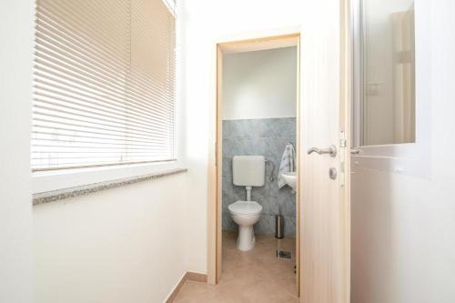 a white bathroom with a toilet and a window at Apartman Ivano in Pula