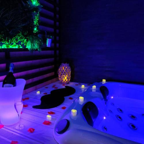 um quarto com uma banheira com velas e uma mesa em La Gaillardise - love room - Spa & Sauna - Espace privatif em Brive-la-Gaillarde