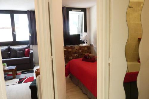 a bedroom with a red bed and a living room at Chamois de Chamonix, Confortable 2 pièces, balcon, parking gratuit in Chamonix-Mont-Blanc