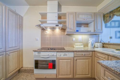 une cuisine avec des armoires en bois et un four à plaques de cuisson dans l'établissement Apartment 60sqm Croisette - Balcony with sea view, à Cannes