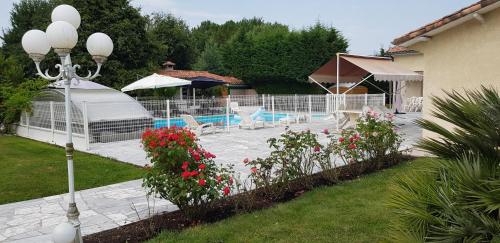 une arrière-cour avec une piscine et un jardin fleuri dans l'établissement Le Cabassou du medoc, à Bégadan