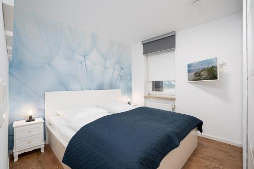 Schlafzimmer mit einem Bett mit blauer Wand in der Unterkunft Ferienwohnung B2 Lieblingsblick in Kellenhusen