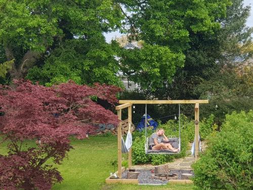 a woman sitting in a swing in a garden at Kingsmede Bed & Breakfast in Ventnor