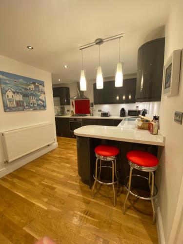 cocina con encimera y 2 taburetes rojos en SeaSure en Bexhill