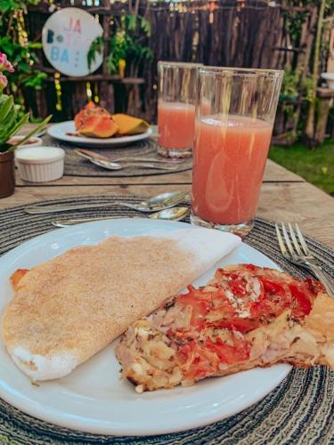 een bord met een stuk pizza en een glas sap bij Pousada Jaboticaba Caraíva in Caraíva