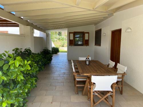 a patio with a wooden table and white chairs at VILLA 21 in Thermisía