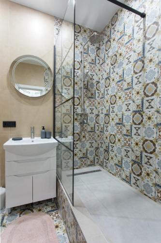 a bathroom with a shower with a sink and a mirror at Naykova district Apartments in Kharkiv