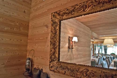an ornate mirror on a wooden wall in a room at Hotel Pedretti in Branzi