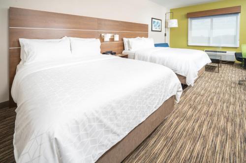 two beds in a hotel room with white sheets at Holiday Inn Express & Suites - Fort Myers Airport by IHG in Fort Myers