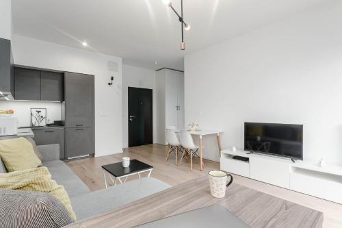 a white living room with a couch and a tv at Chill Apartments Mokotów Residence in Warsaw