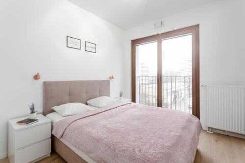 a white bedroom with a large bed and a window at Chill Apartments Mokotów Residence in Warsaw