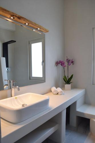 La salle de bains blanche est pourvue d'un lavabo et d'un miroir. dans l'établissement Eight senses, à Parikia