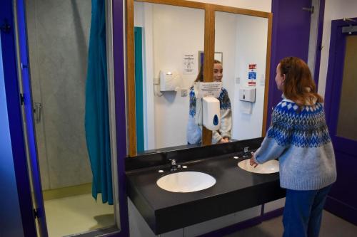een vrouw die voor een wastafel in een badkamer staat bij Royal Mile Backpackers in Edinburgh