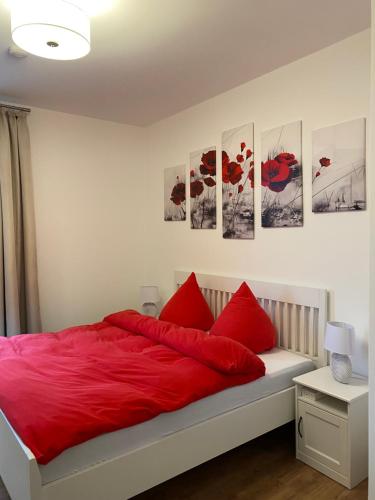 1 dormitorio con almohadas rojas y cuadros en la pared en Schwartz GmbH en Greiz