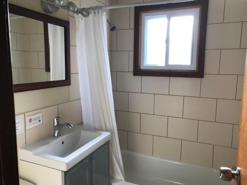 een badkamer met een wastafel, een bad en een raam bij Hush Lodge and Cottages 