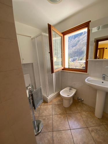 uma casa de banho com um lavatório, um WC e uma janela. em Ca del Nore em Fontainemore