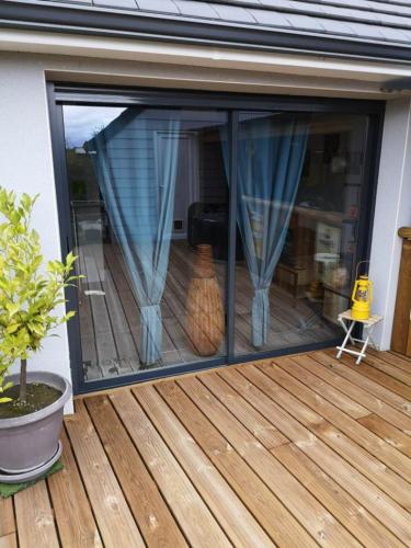 eine Glasschiebetür auf einem Deck mit einer Katze im Innenbereich in der Unterkunft Dépendance Les Ecloses in Chailloué