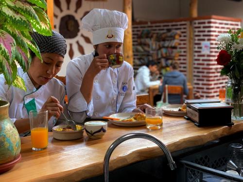 two chefs sitting at a table eating food at Hostal Yakumama in Cuenca