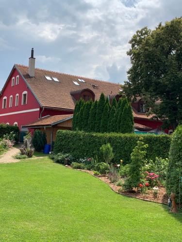 a red house with a yard with bushes and trees at Hotel Penzion Trámky in Vikýřovice