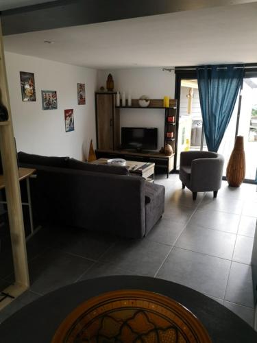 ein Wohnzimmer mit einem Sofa und einem TV in der Unterkunft Dépendance Les Ecloses in Chailloué