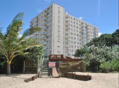 a large building on the beach with a palm tree at 104 Santana Resort, Margate Beach in Margate