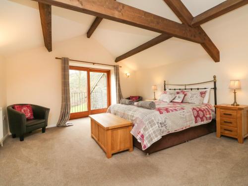 a bedroom with a bed and a chair and a window at Red Deer Cottage in Minehead