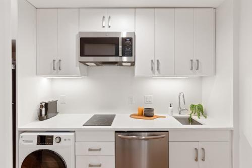 a white kitchen with a sink and a microwave at The Iris in Charleston
