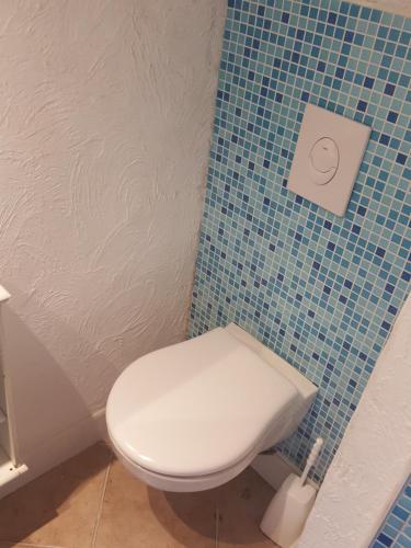 a bathroom with a toilet and a blue tiled wall at Die alte Schule Häuschen in Saint-Vith