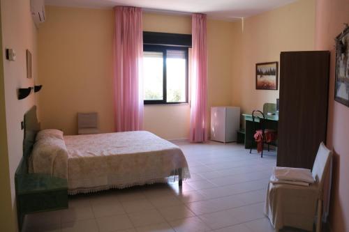 una camera con letto e finestra con tende rosa di Hotel Mater Mediterranea a Senorbì