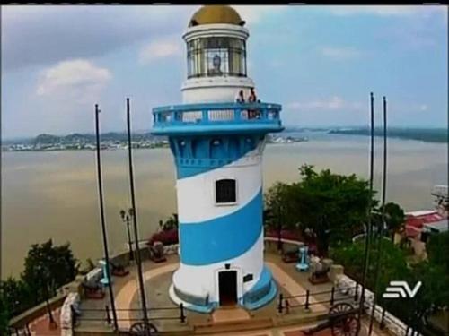 a blue and white lighthouse in front of the water at Ecusuites Puerto Santa Ana - River Junto a Hotel Wyndham in Guayaquil