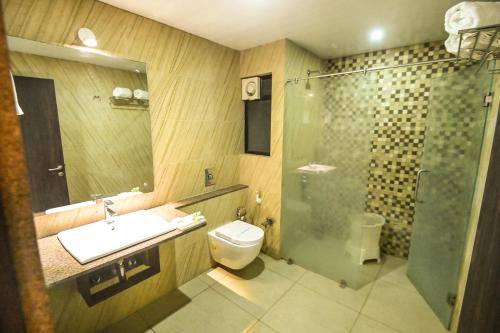 a bathroom with a shower and a toilet and a sink at The Divine Resort Somnath in Somnath