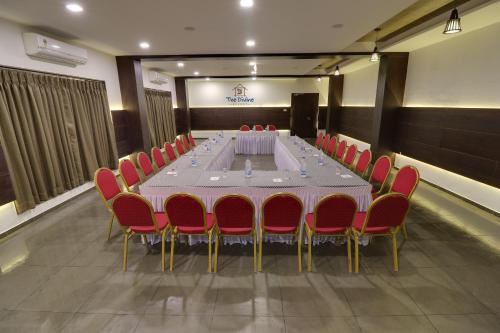 a conference room with a long table and red chairs at The Divine Resort Somnath in Somnath