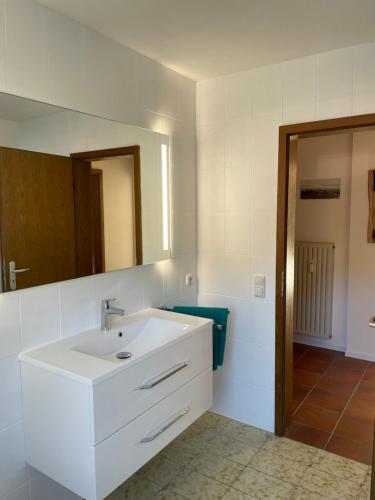 uma casa de banho com um lavatório branco e um espelho. em Großzügiges Domizil, 90qm, mit Terrasse, Garten und Garage em Marquartstein
