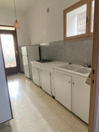 een witte keuken met een wastafel en een koelkast bij Chez Cathy et Alain in Saint-Laurent-dʼAigouze