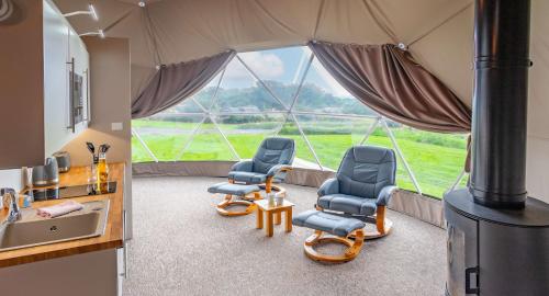 a room with three chairs and a large window at Brynteg Glamping in Llanallgo