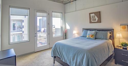 a bedroom with a bed with blue sheets and windows at 2BR Fully Furnished Apartment - Great location in Midtown apts in Atlanta