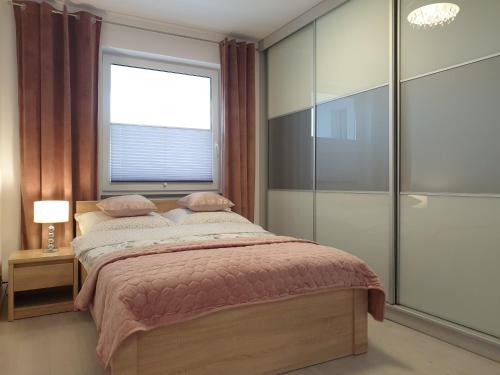 a bedroom with a large bed and a window at Caskada Modern Apartment 3 in Słupsk