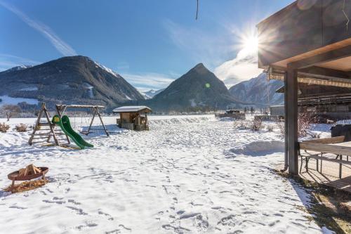 a playground in the snow with mountains in the background at Gästehaus Dreier in Neukirchen am Großvenediger