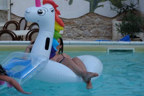 a woman riding on an inflatable unicorn in a pool at Morfeo Charming Rooms & Relax in Avola