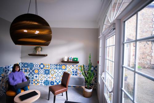 a woman sitting on a couch in a room with a window at Hotel - Restaurant Les 3 Piliers in Le Boupère