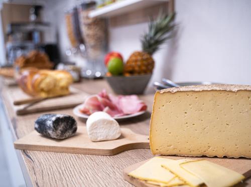 a counter with cheese and fruit on a cutting board at Hotel - Restaurant Les 3 Piliers in Le Boupère