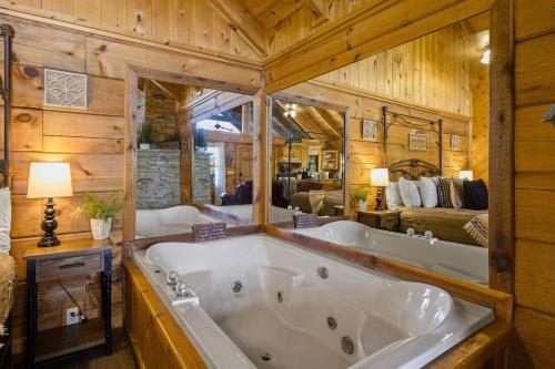 a large white tub in a room with a bedroom at Cozy Studio Log Cabin in the heart of Pigeon Forge. Hot Tub. Honeymoon! Sleeps 2 in Pigeon Forge
