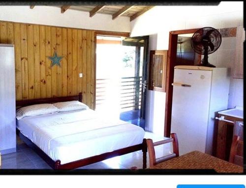 a bedroom with a white bed and a refrigerator at Pousada Carpe Diem in Imbituba
