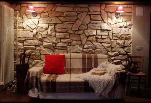 pared de piedra con cama con almohada roja en 2 bedrooms chalet with sauna enclosed garden and wifi at Gratillon, en Villeneuve