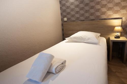 a hotel room with a bed with towels on it at Hôtel Beaulieu in Clermont-Ferrand
