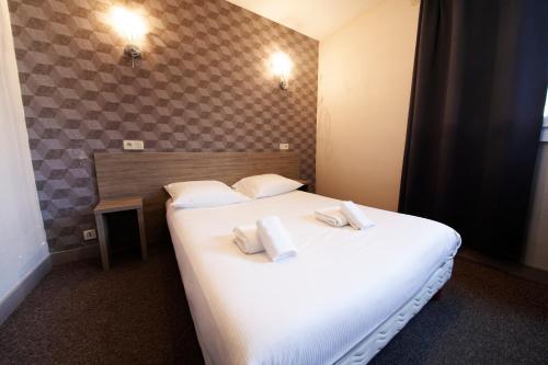 een slaapkamer met een groot wit bed en handdoeken bij Hôtel Beaulieu in Clermont-Ferrand